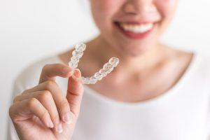 woman holding Invisalign tray 