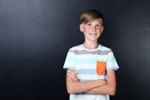 young boy with metal braces in front of blackboard