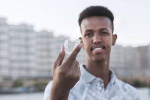 young man holding on Invisalign tray 