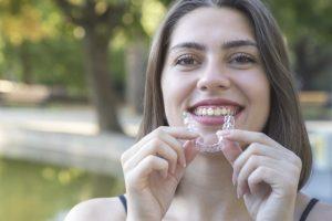 young smiling woman holding Invisalign tray 