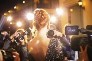 woman surrounded by photographers on red carpet 