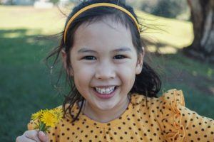 young girl with slightly crooked teeth outside 